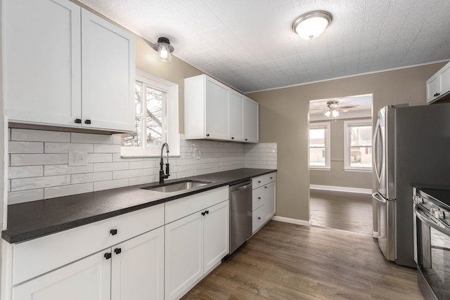 kitchen featuring sink, dark wood-type flooring, stainless steel appliances, white cabinets, and decorative backsplash