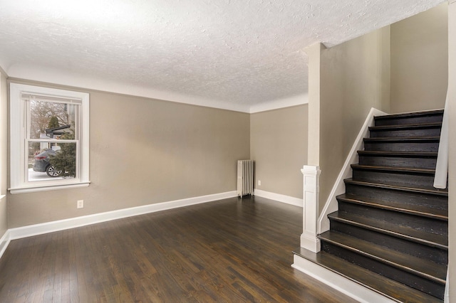 empty room with radiator heating unit, dark hardwood / wood-style flooring, and a textured ceiling