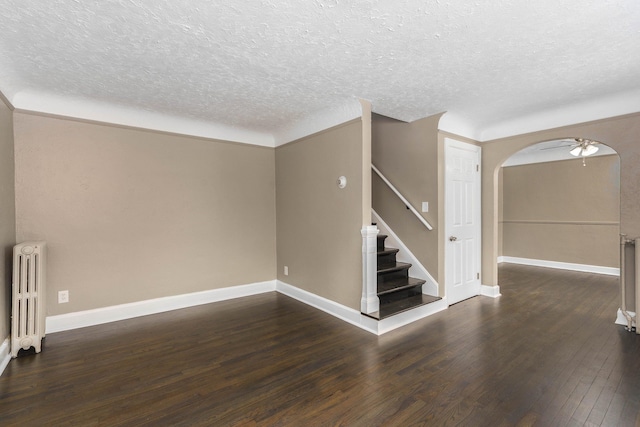 spare room featuring dark hardwood / wood-style flooring, radiator, a textured ceiling, and ceiling fan