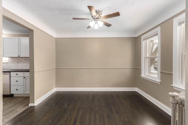 unfurnished room featuring ceiling fan, dark hardwood / wood-style flooring, radiator, and a textured ceiling