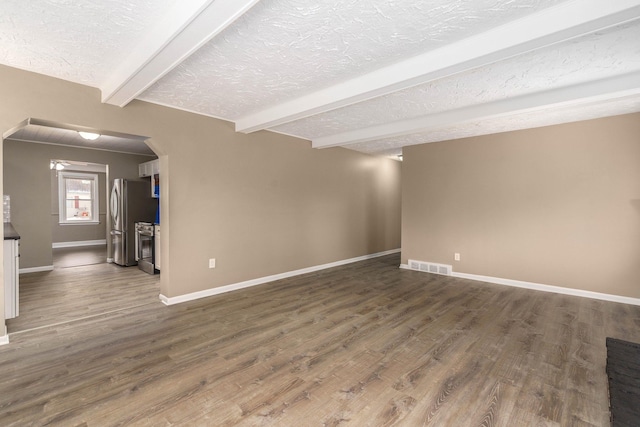 unfurnished living room with beamed ceiling, dark hardwood / wood-style floors, and a textured ceiling