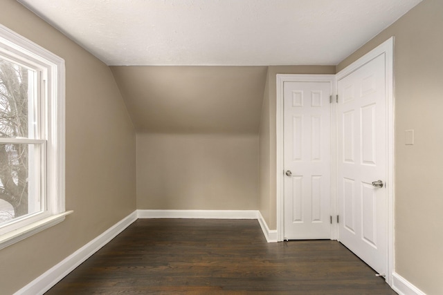 bonus room with dark hardwood / wood-style flooring and vaulted ceiling