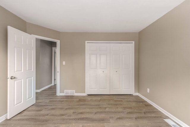 unfurnished bedroom with light wood-type flooring and a closet