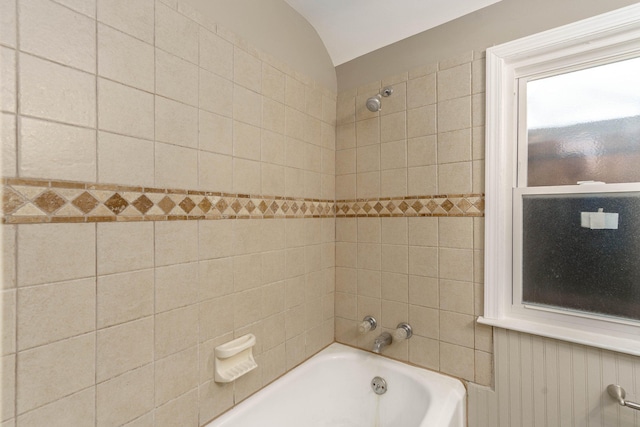 bathroom with tiled shower / bath combo and vaulted ceiling