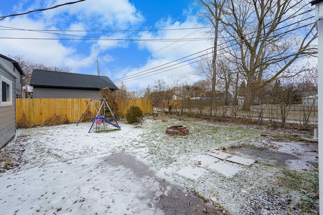 snowy yard with a fire pit and a playground