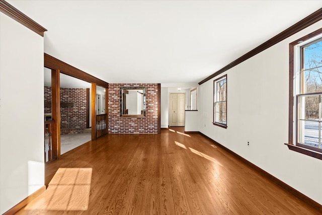 unfurnished living room with crown molding, hardwood / wood-style flooring, and brick wall