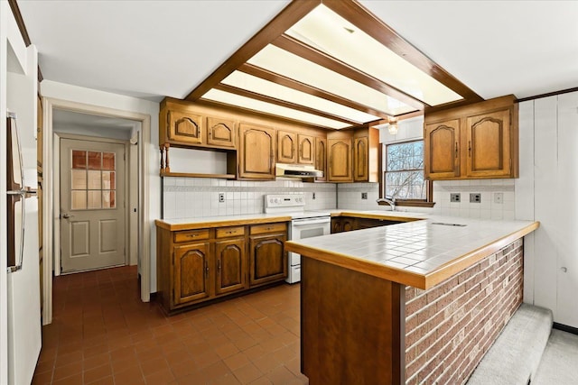 kitchen with tasteful backsplash, white appliances, tile counters, and kitchen peninsula