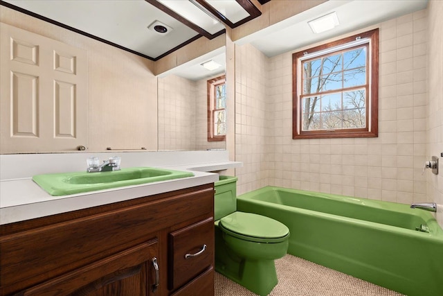 bathroom with a washtub, vanity, and toilet