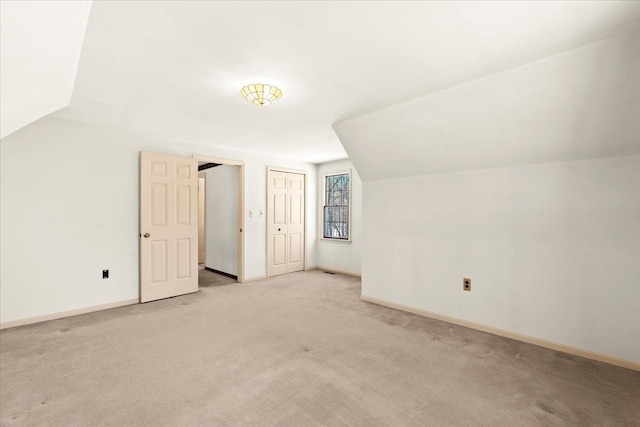 additional living space featuring light colored carpet and lofted ceiling