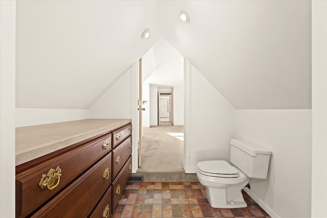 bathroom with lofted ceiling and toilet