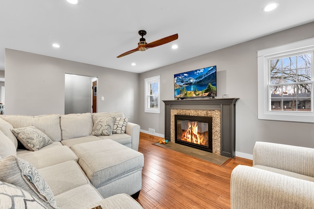 living room featuring a tile fireplace, wood-type flooring, and ceiling fan