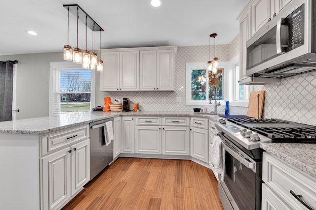 kitchen with kitchen peninsula, white cabinets, and appliances with stainless steel finishes