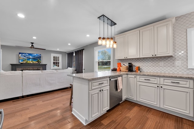 kitchen featuring pendant lighting, stainless steel dishwasher, light wood-type flooring, and kitchen peninsula