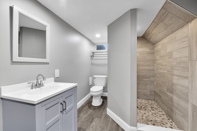 bathroom featuring vanity, toilet, hardwood / wood-style floors, and a tile shower