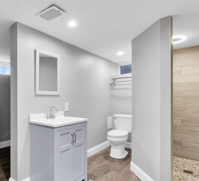 bathroom with walk in shower, vanity, toilet, and hardwood / wood-style floors