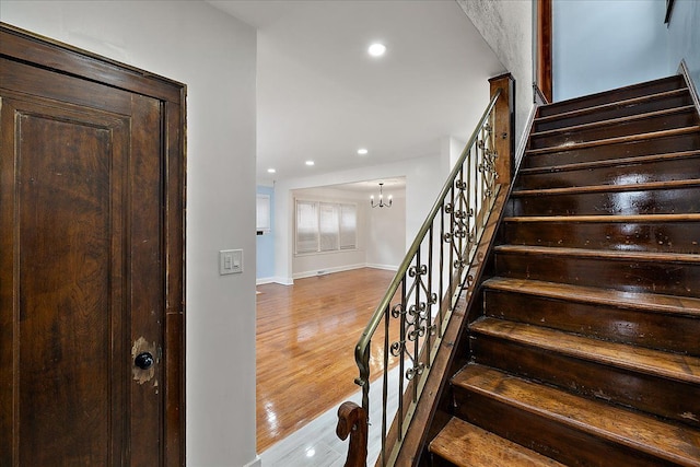 stairs featuring wood-type flooring and a chandelier