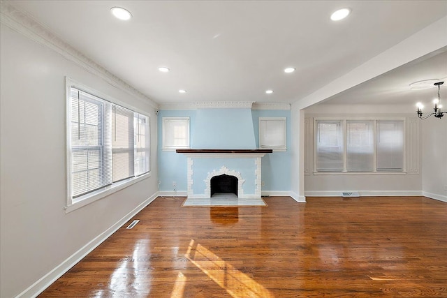 unfurnished living room with hardwood / wood-style floors, crown molding, and a chandelier