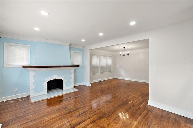 unfurnished living room with an inviting chandelier, hardwood / wood-style floors, and a fireplace