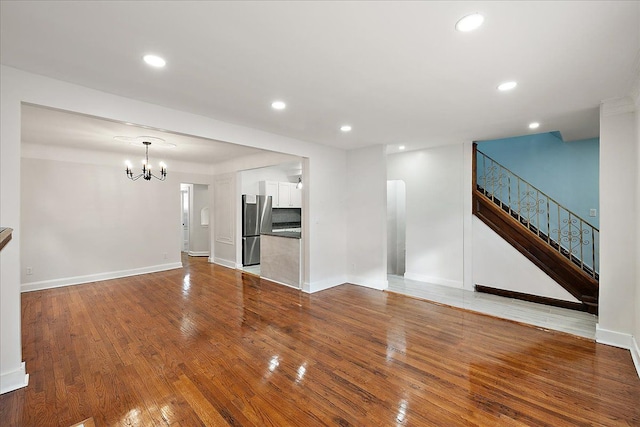 unfurnished living room featuring an inviting chandelier and wood-type flooring