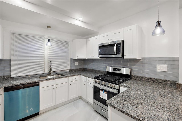 kitchen with sink, white cabinetry, decorative light fixtures, dark stone countertops, and appliances with stainless steel finishes