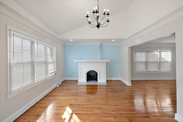 unfurnished living room featuring lofted ceiling, a large fireplace, a chandelier, light hardwood / wood-style floors, and crown molding