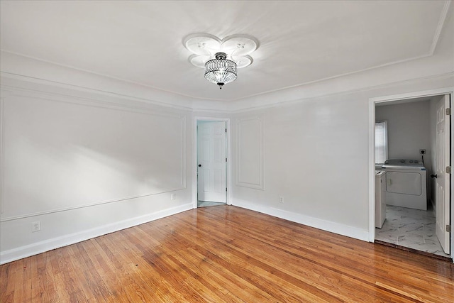 empty room featuring washing machine and clothes dryer and light wood-type flooring