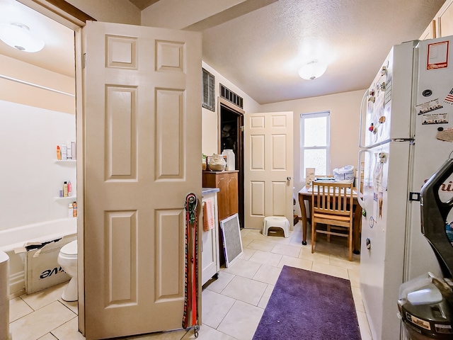 bathroom with a textured ceiling, tile patterned floors, shower / bathtub combination, and toilet