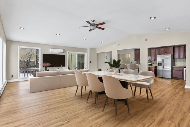 dining space featuring vaulted ceiling, plenty of natural light, a wall mounted AC, and light hardwood / wood-style floors