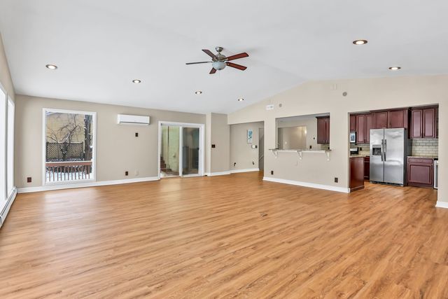 unfurnished living room with ceiling fan, lofted ceiling, light hardwood / wood-style flooring, and an AC wall unit