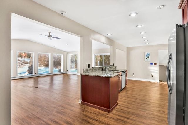 kitchen featuring vaulted ceiling, dark hardwood / wood-style floors, sink, light stone counters, and stainless steel appliances