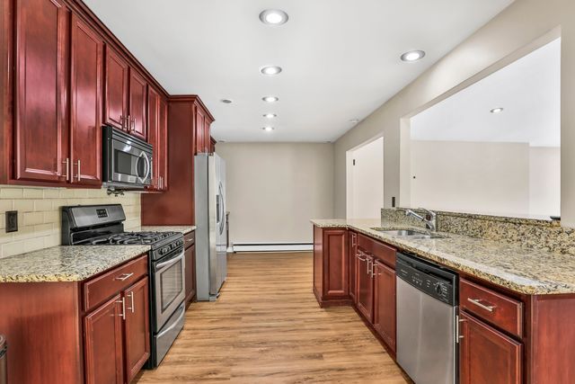 kitchen with light stone counters, sink, kitchen peninsula, and appliances with stainless steel finishes