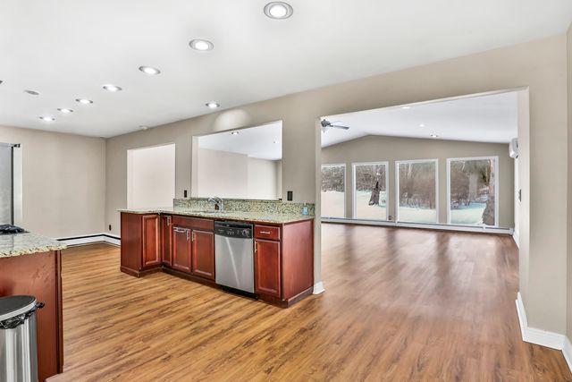 kitchen featuring sink, light stone countertops, stainless steel dishwasher, kitchen peninsula, and light wood-type flooring