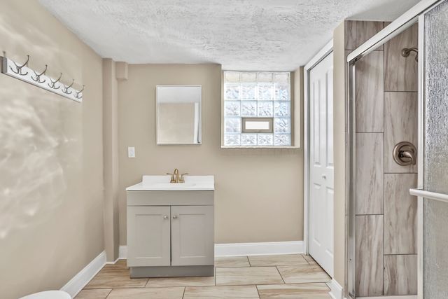 bathroom with vanity, an enclosed shower, and a textured ceiling