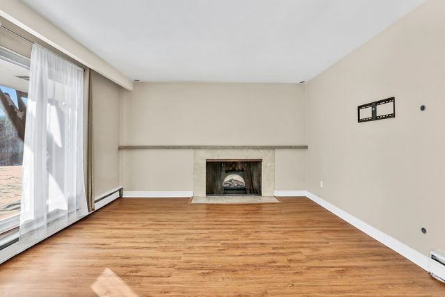 unfurnished living room with plenty of natural light, light hardwood / wood-style floors, and baseboard heating