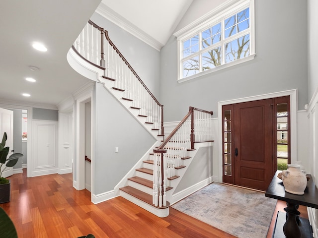 foyer featuring high vaulted ceiling, ornamental molding, and light wood-type flooring