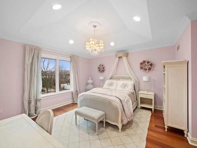 bedroom with hardwood / wood-style flooring, ornamental molding, an inviting chandelier, and a tray ceiling