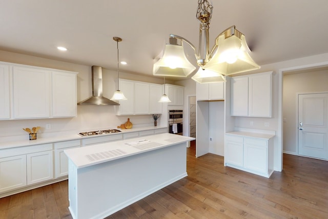 kitchen featuring white cabinetry, hanging light fixtures, wall chimney exhaust hood, and appliances with stainless steel finishes