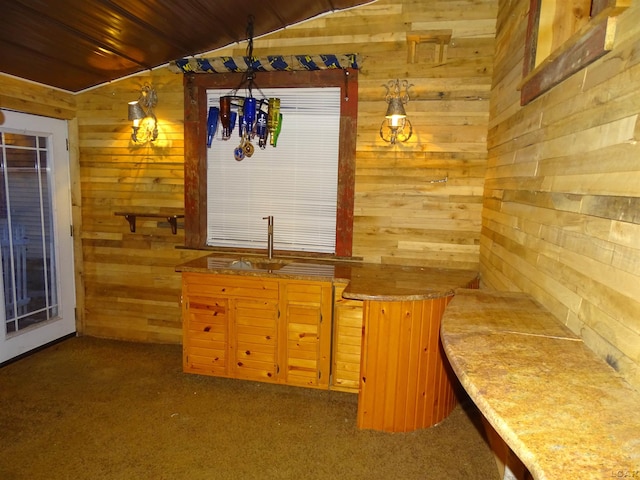 bar with dark colored carpet, wood ceiling, vaulted ceiling, and wood walls