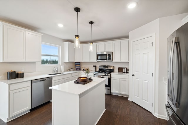 kitchen featuring a kitchen island, appliances with stainless steel finishes, pendant lighting, sink, and white cabinets