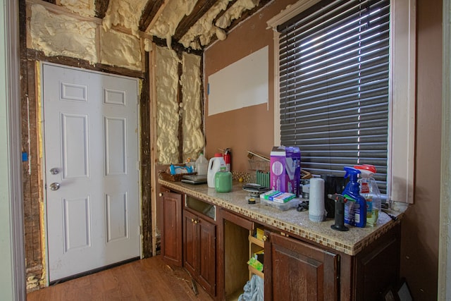 bar featuring wood-type flooring, built in desk, and light stone countertops