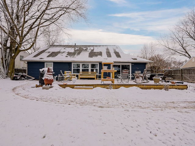 snow covered back of property featuring a garage and a wooden deck