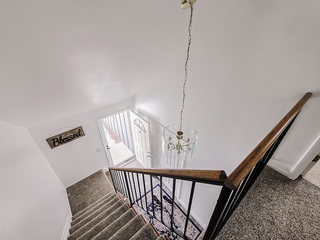 staircase with carpet floors and a notable chandelier