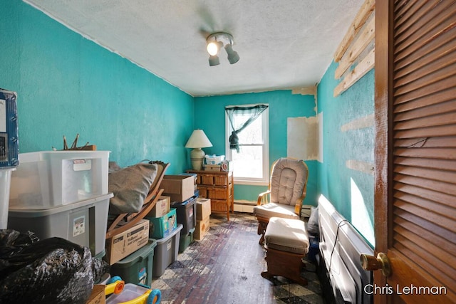 interior space featuring wood-type flooring, a textured ceiling, and baseboard heating