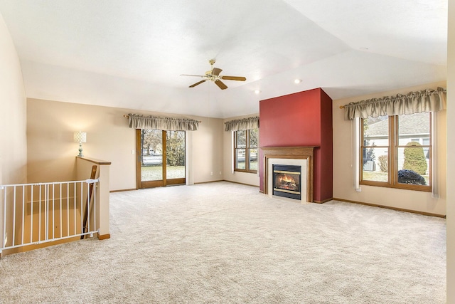 unfurnished living room with vaulted ceiling, light carpet, ceiling fan, and a tray ceiling