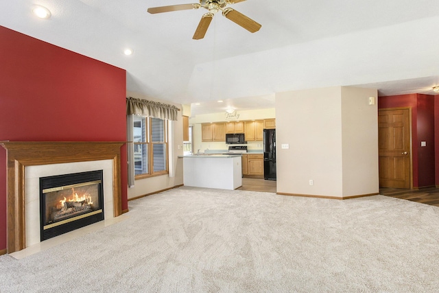 unfurnished living room with vaulted ceiling, light carpet, and ceiling fan