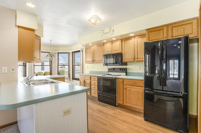 kitchen featuring pendant lighting, black appliances, sink, light hardwood / wood-style floors, and kitchen peninsula