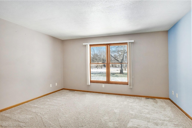 empty room with carpet floors and a textured ceiling