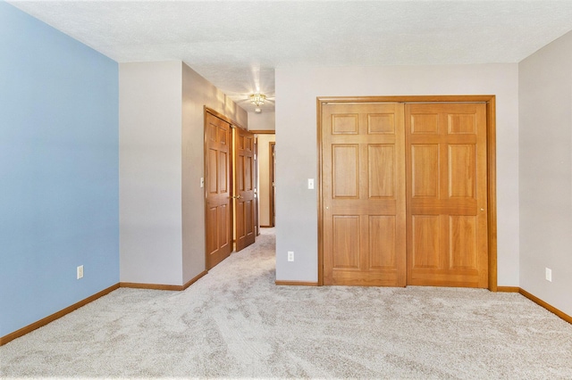 unfurnished bedroom featuring a closet, light carpet, and a textured ceiling