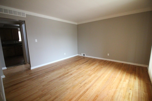 empty room with crown molding and hardwood / wood-style floors