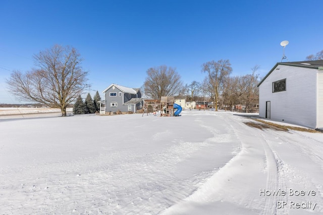 yard layered in snow featuring a playground